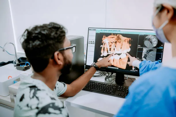 Dentiste expliquant une imagerie 3D des dents à son patient sur écran
